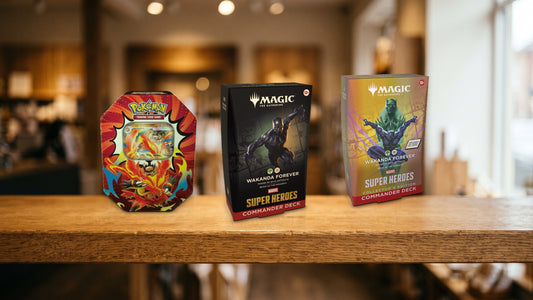 Pokemon Mega Emboar ex tin and two Wakanda Forever Commander Decks on a wooden shop shelf